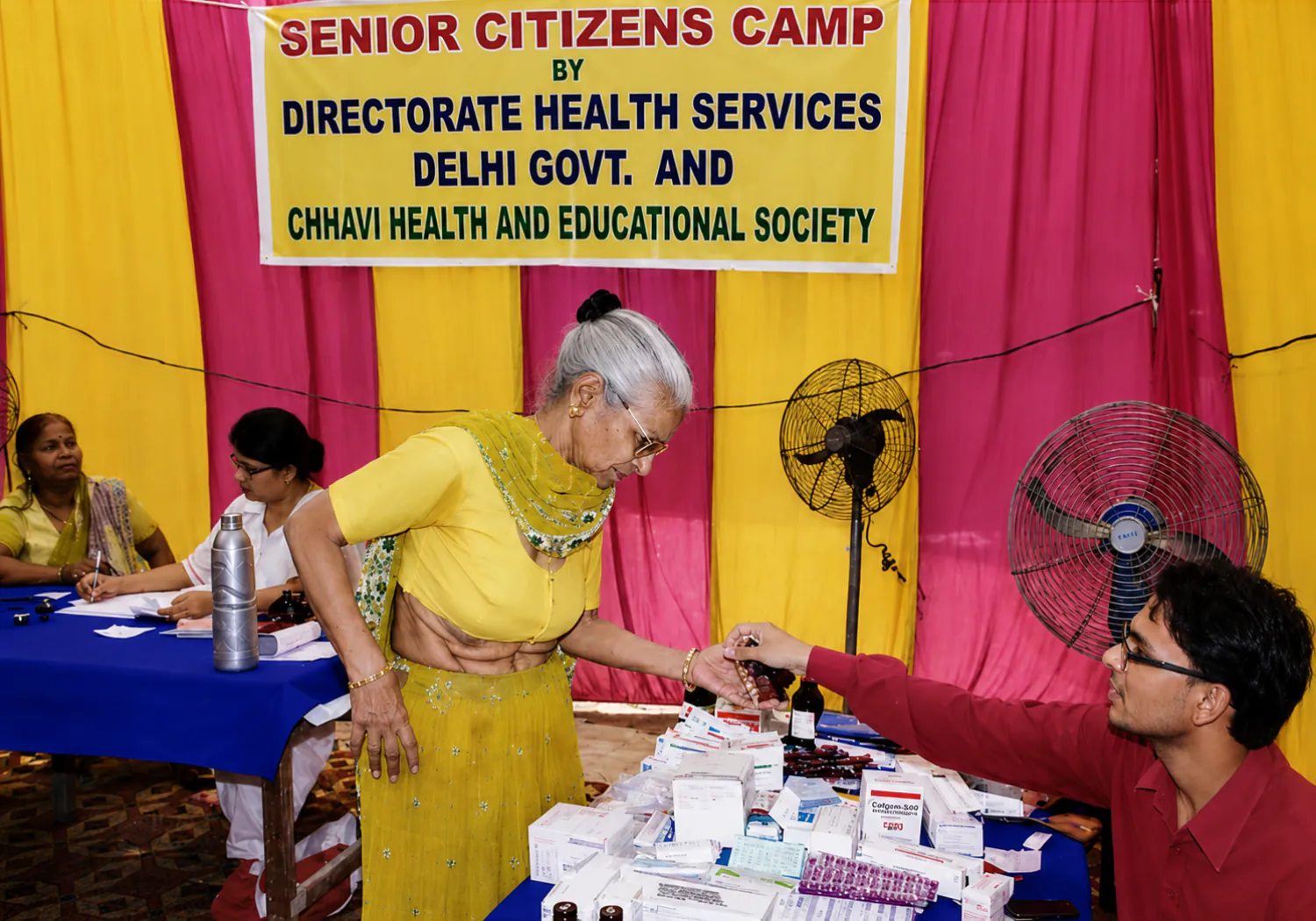 CHES staff dispensing medicines to an elderly woman at a community medical camp
